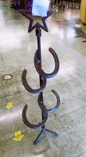 HORSE SHOES welded into a stand with star on top.  Not sure - umbrella stand?  cane holder?  fishing poles?  
$19.80