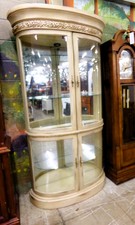 CURIO.  Has curved glass doors and glass shelves.  Lighted.  Is half-moon shape with mirrored backing.  7 ft tall, 42